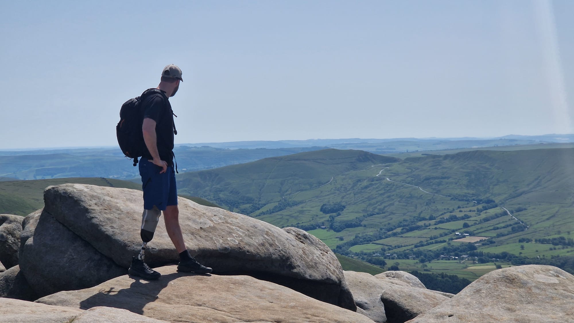 Chay Coulbert standing on a rocky outcrop overlooking rolling hills